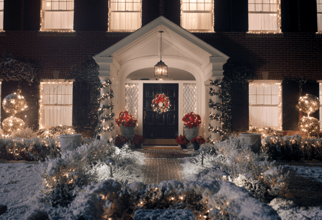 A warmly lit house decorated with holiday lights in the evening.