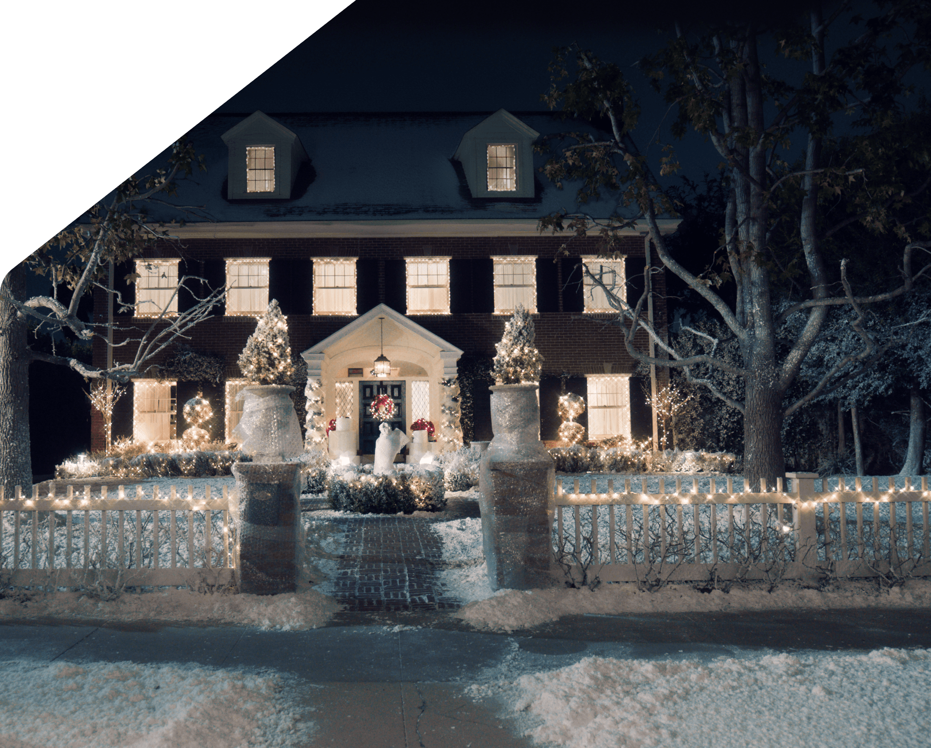 A warmly lit house decorated with holiday lights in the evening.