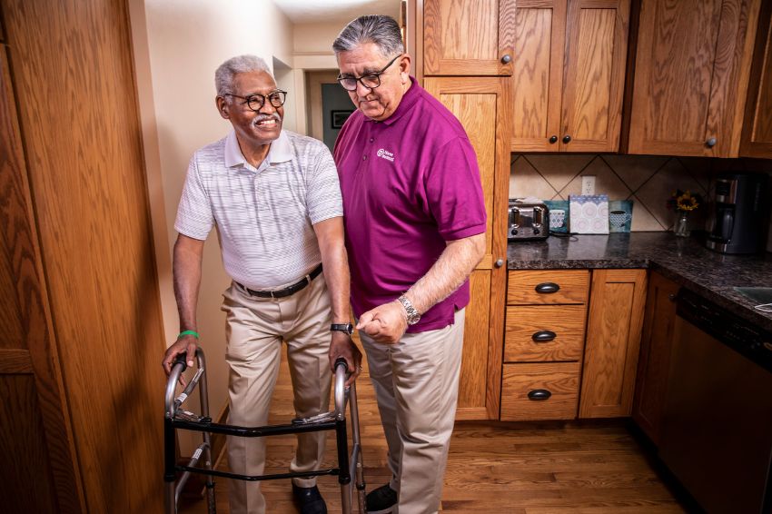 Home Instead Caregiver walking alongside a senior on walker