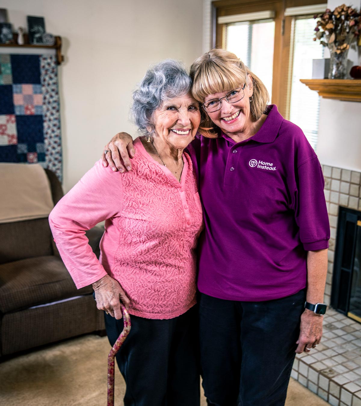 Home Instead CAREGiver and senior standing together smiling in home