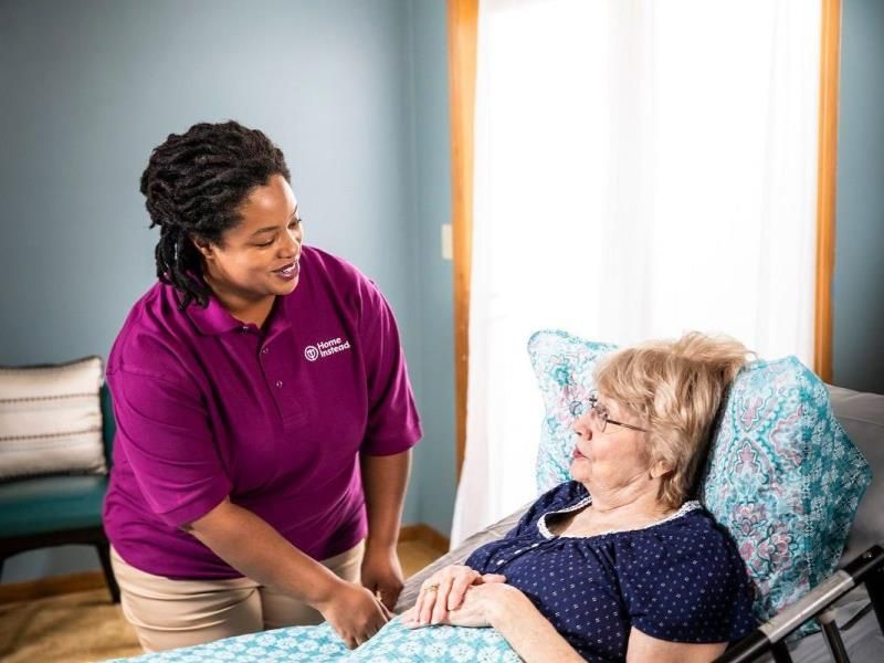 Home Instead caregiver comforting senior client laying in bed