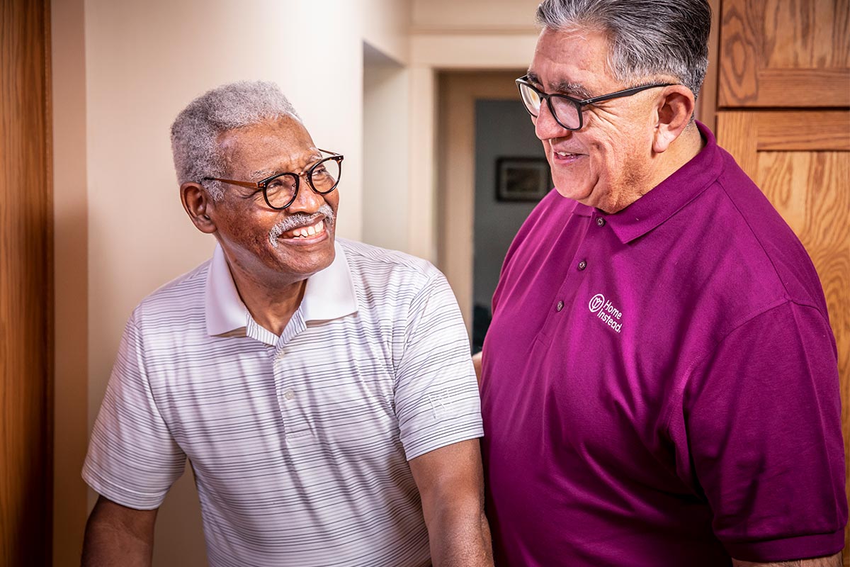 home instead caregiver helps senior man walking at home