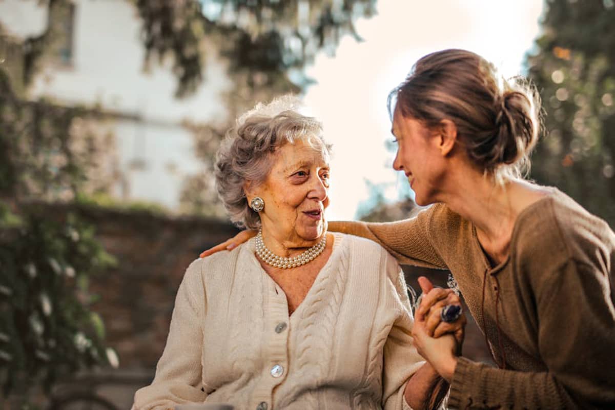 Senior with Alzheimers and their Family Caregiver sitting in a garden 1 