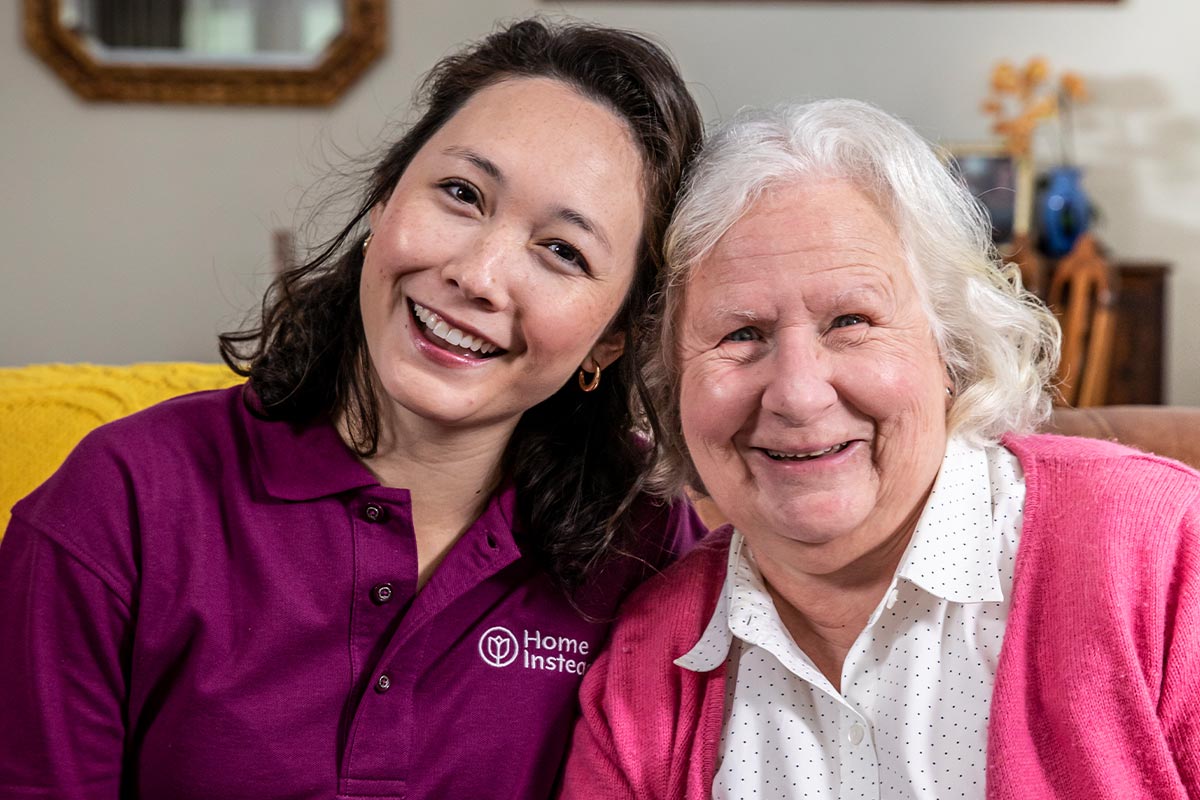 Home Instead CAREGiver and senior sitting together smiling