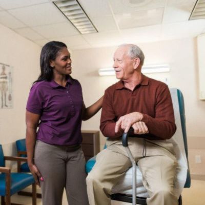 smiling caregiver assisting senior client at doctors office